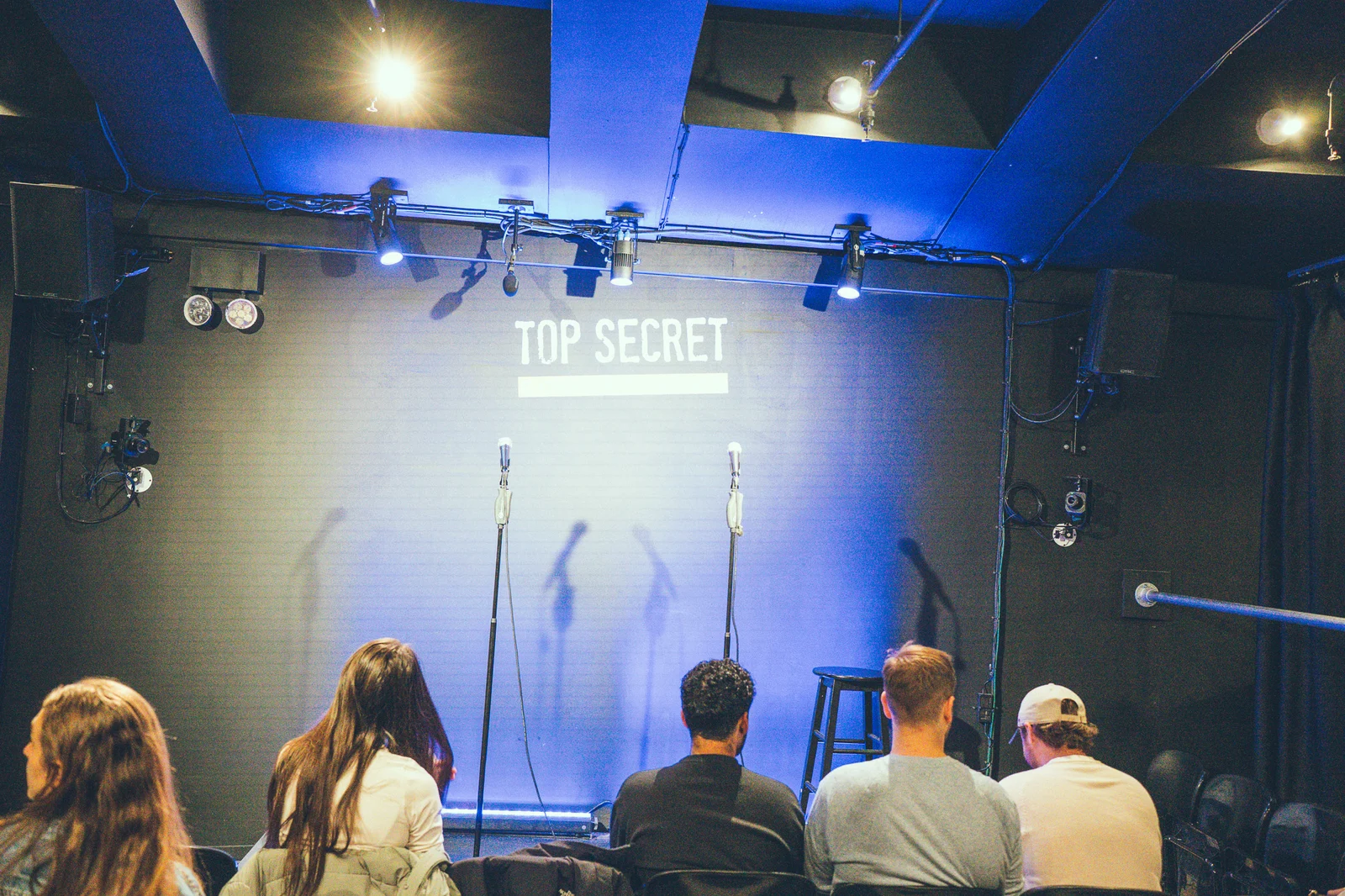 Audience members take their seats facing two microphones and the blue-lit Top Secret stage.
